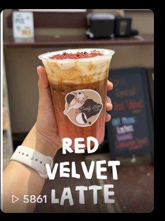A red velvet latte topped with red crumble in an Early Bird logo cup.